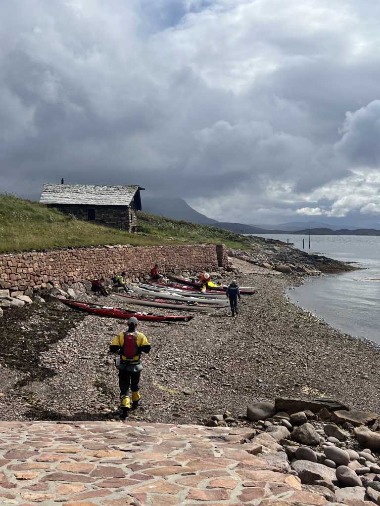 Kayaks pulled up at The Anchorage on Tanera Mor, restored stone building and dyke work behind